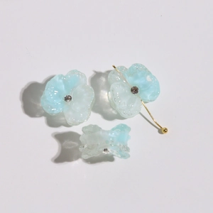 Macro shot of three blue translucent flower resin charms with rhinestones and gold pins