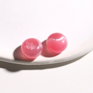Detail of pink resin beads with cat-eye effect on white textured jewelry display tray