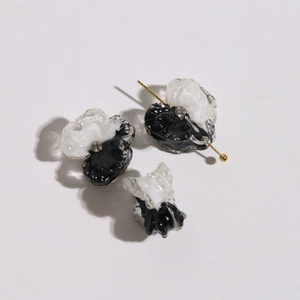 Detailed macro of black and white flower charms with resin petals and inset rhinestones