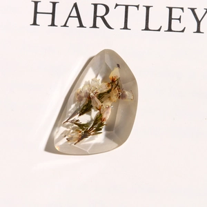 Macro shot of clear resin faceted stone with embedded dried flowers for DIY jewelry making