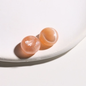 Macro detail of 15mm round peach resin cabochons with iridescent shimmer and pearly finish
