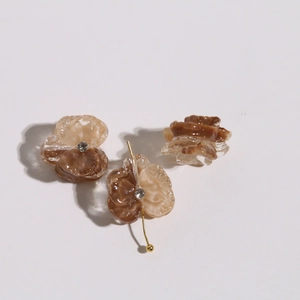 Close-up of amber resin flower charms with clear rhinestones and golden metal hooks