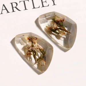 Macro detail of transparent resin charms with dried purple flowers and green plants