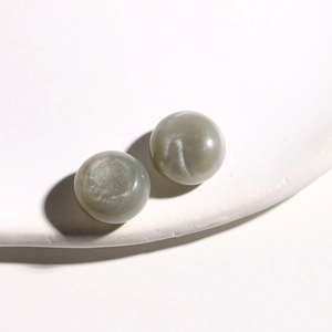 Detailed view of 15mm sage green resin beads with subtle glitter on a white stand