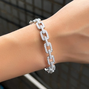 Macro-opname van een zilveren schakelarmband met micro-pavé zirkonia op vierkante schakels