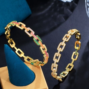Detailopname van gouden schakelarmbanden met gekleurde en heldere zirkonia edelstenen