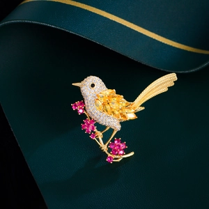 Detailed macro view of a bird brooch with colorful zircons on a dark green surface
