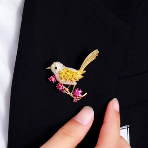 Artistic bird brooch with colorful zircons on floral branch pinned to a black suit lapel