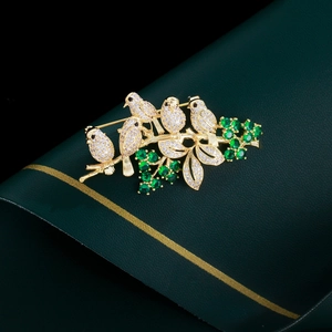 Detailed macro view of gold-plated bird brooch featuring micro-set white and green zircons
