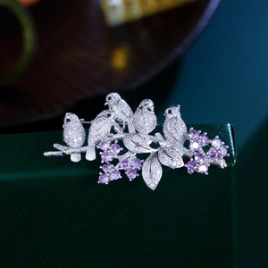 Exquisite silver bird brooch with white zircons and purple gems on a jewelry display box