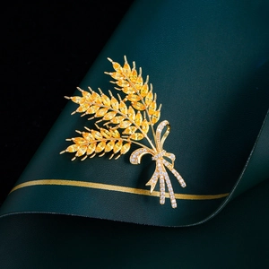 Macro detail of golden wheat ear brooch with yellow zircons and crystal bow on green leather