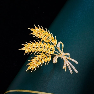 Macro view of a gold wheat brooch with amber gems and crystal bow on green leather