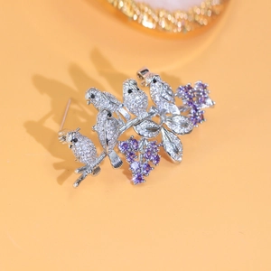 Detailed view of silver bird brooch with white zircon pave and purple gemstones
