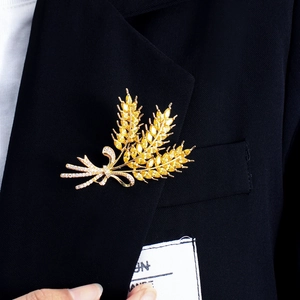 Elegant gold wheat brooch with yellow stones and bow on a black blazer lapel