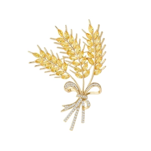Elegant gold wheat brooch with yellow stones and diamond bow on a white background