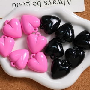 Makro-Detail von glänzenden rosa und schwarzen Herzanhängern für DIY-Schmuck
