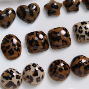Platte weergave van hars kralen met luipaardprint in hart-, ster- en geometrische vormen