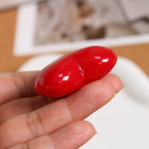 Macro detail of glossy red heart-shaped charm featuring a side hole for DIY jewelry