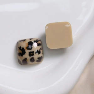 Detail van vierkante luipaard- en beige harsbedeltjes op een wit keramisch bordje