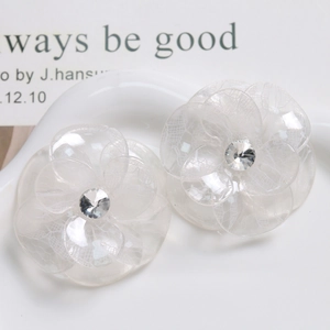 Detail of transparent acetate flower accessory with lace texture and center rhinestone