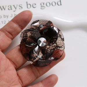 Detail of brown acetate flower hair accessory with lace pattern and central crystal