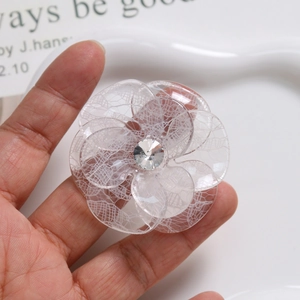 Close-up of a large acetic acid flower hair accessory with lace texture and rhinestone