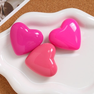 Three vibrant pink 3D heart pendants displayed on a white ceramic plate for DIY accessories