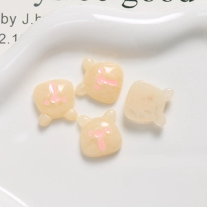 Macro shot of four cream-yellow resin bears on a ceramic tray for DIY craft accessories