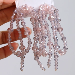 Détail de boucles d'oreilles pompons en cristal lavande sur carte de présentation