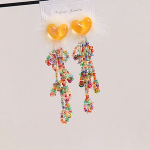 Detail of colorful tassel earrings with orange heart and white faux fur on display card