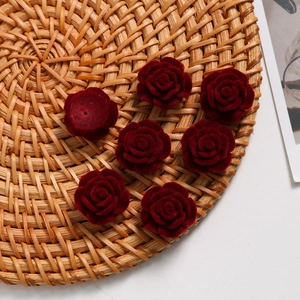 Detailed view of burgundy flocked rose heads for DIY jewelry with back perforation