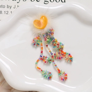 Detail of sweet orange heart plush accessory with colorful bead tassels and sequins