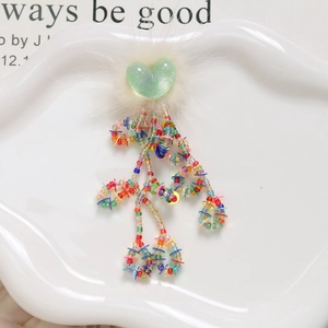 Close-up of heart-shaped glitter charm with faux fur and colorful beaded tassels