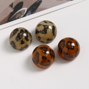 Makroaufnahme von vier hochglänzenden Acryl-Anhängern mit Leopardenmuster für DIY-Schmuck