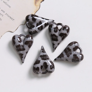 Gros plan de 5 pendentifs coeur en résine imprimé léopard pour la création de bijoux DIY