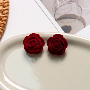 Detailed view of dark red velvet rose earrings on an elegant ceramic jewelry tray