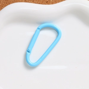 Close-up of a light blue D-shaped aluminum spring hook on a white ceramic plate