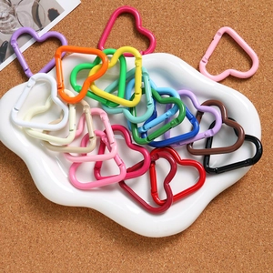 Colorful macaron heart-shaped alloy spring buckles in a decorative white tray on cork