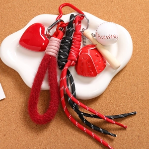Mini baseball keychain set with bat, glove, and heart charm on cork background