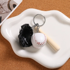 Detailed view of mini baseball, glove, and wooden bat keychain on a ceramic tray