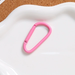 Close-up of pink macaron D-ring spring carabiner on a decorative ceramic plate
