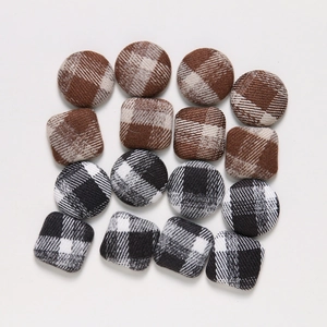 Flat lay of plaid fabric covered round and square buttons for DIY craft hair accessories