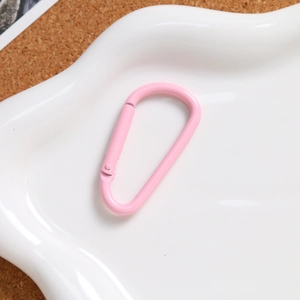 Detail of pink matte D-ring aluminum spring hook on an elegant ceramic wave tray