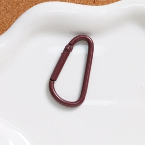 Close-up of deep red D-ring carabiner with spring gate on a ceramic tray