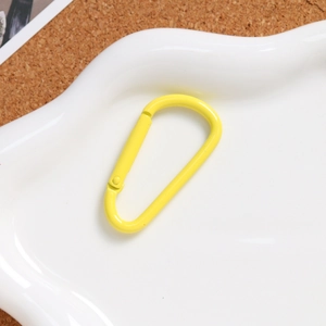Close-up of bright yellow D-shaped aluminum alloy spring carabiner on a white tray
