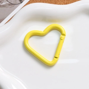 Macro shot of a bright yellow heart-shaped spring clasp on a white wavy ceramic plate