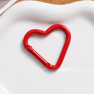 Macro shot of red heart-shaped alloy spring clasp on a white tray for DIY accessories
