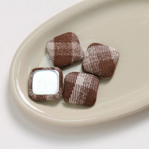 Macro detail of square brown checkered fabric buttons with flat metal base for DIY hair accessories