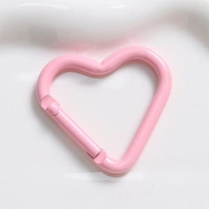 Macro view of a heart-shaped pink carabiner hook with a spring gate for DIY keychains