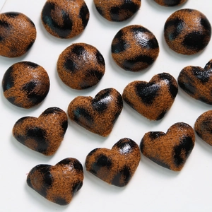 Macro view of leopard print heart and round fabric-covered buttons for DIY accessories